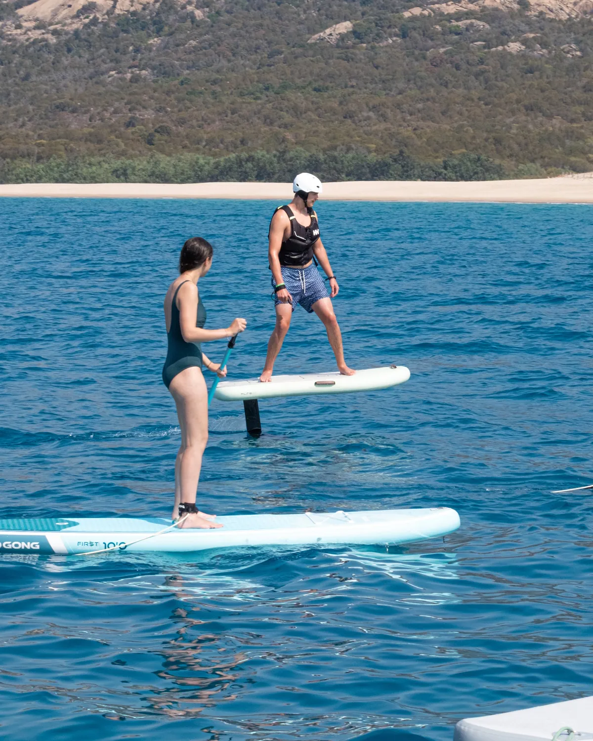 Guests on an e-foil and a paddleboard near the beach