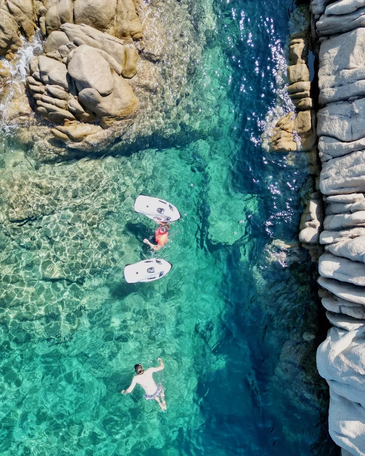 Guests snorkelling in clear water between granite rocks
